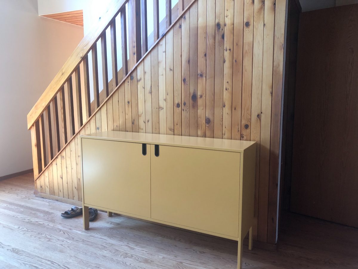 A yellow waist-high cabinet on a wood-paneled wall.